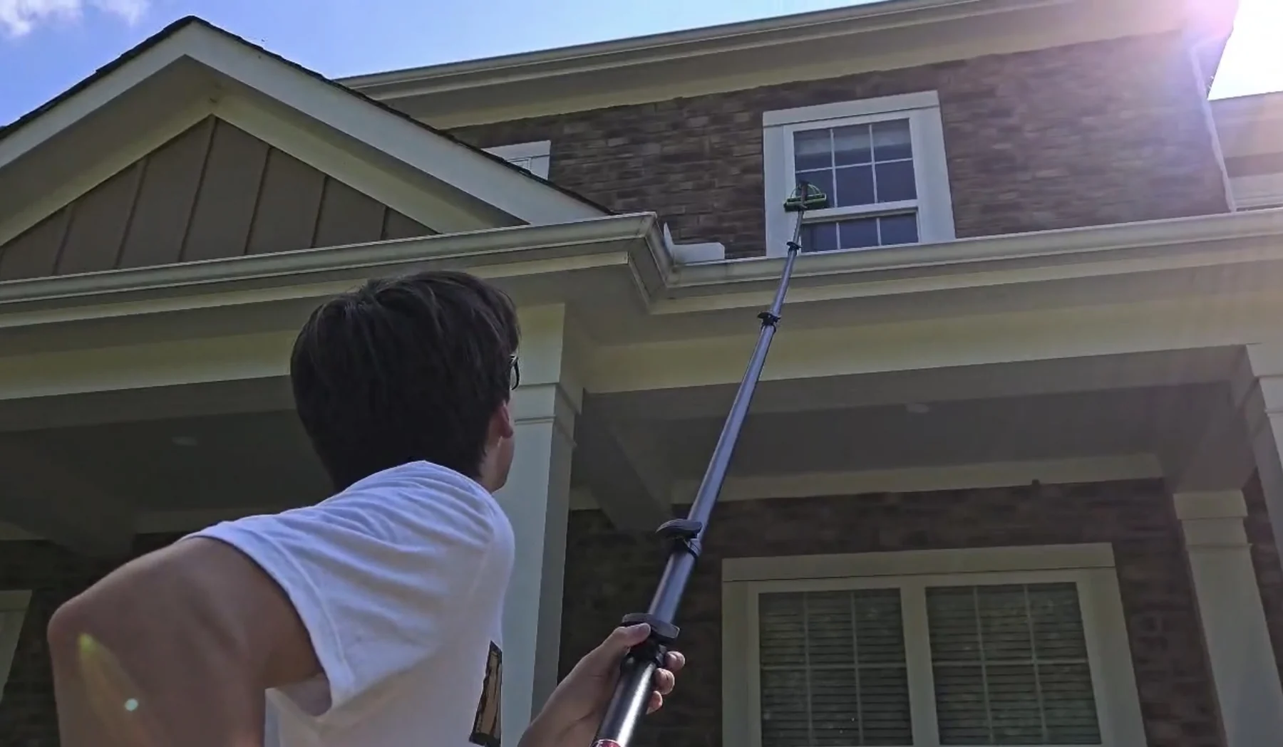 Motion Washing cleaning a second-story exterior window with a water-fed pole